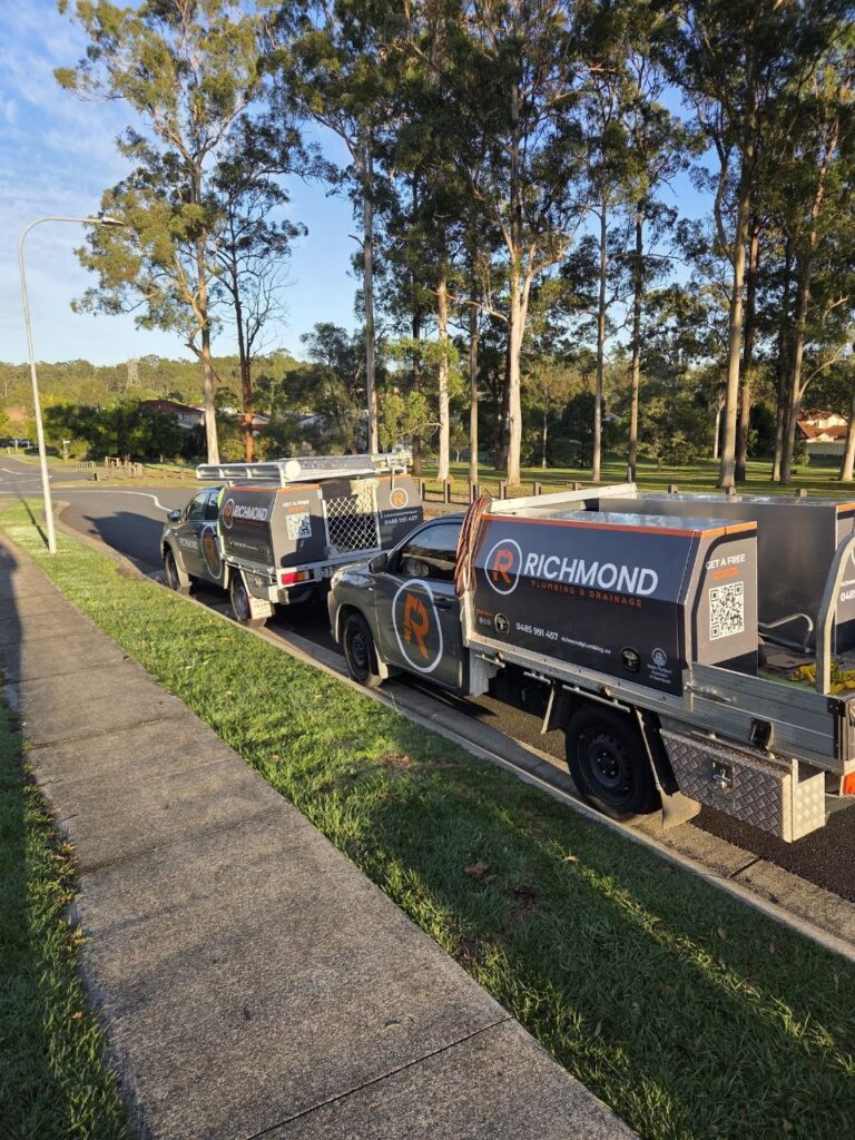 Two Richmond Plumbing & Drainage service trucks parked on a residential street side